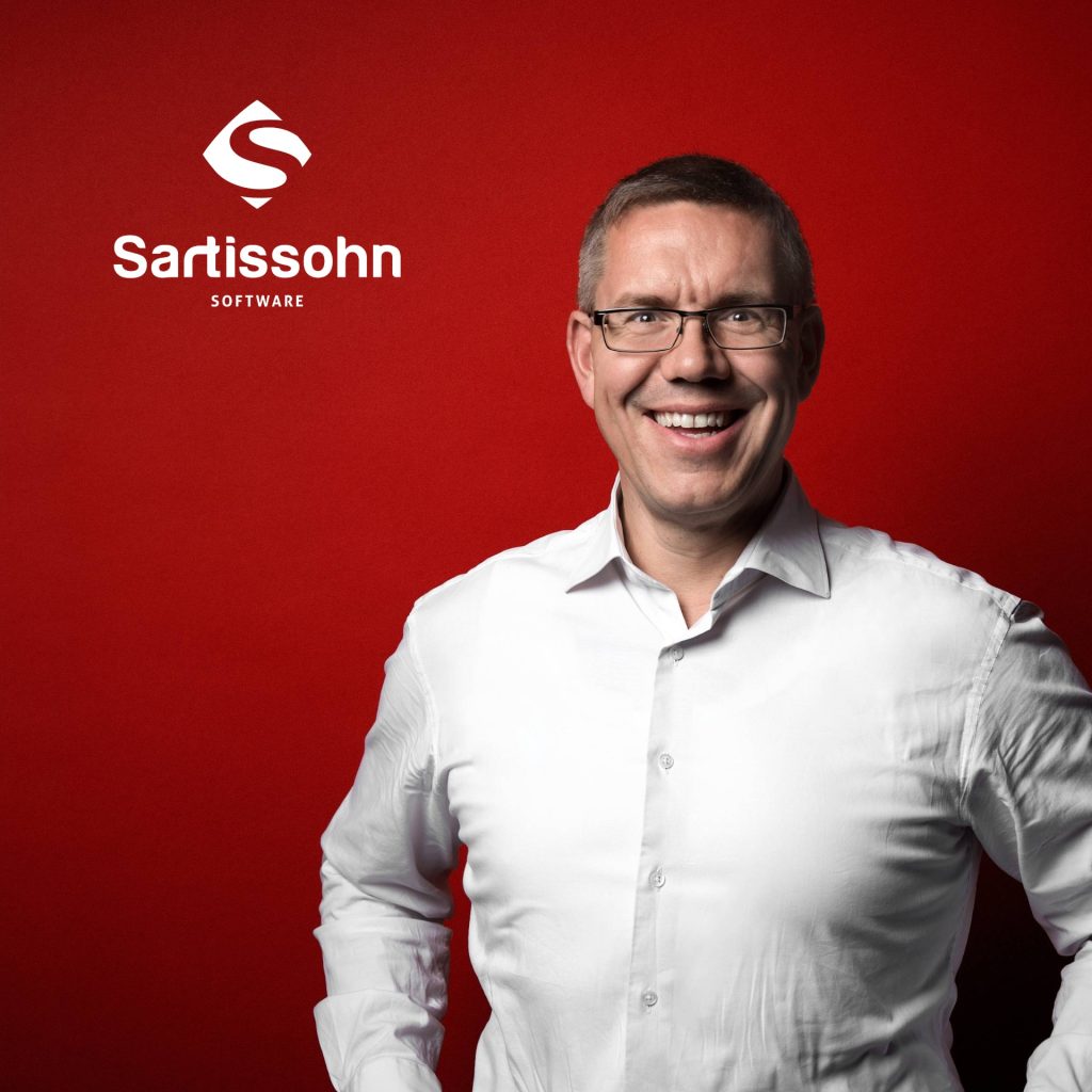 Portrait vor rotem Hintergrund mit Logo: Gründer und Geschäftsführer Mike Olaf Sartissohn von der Sartissohn Software GmbH